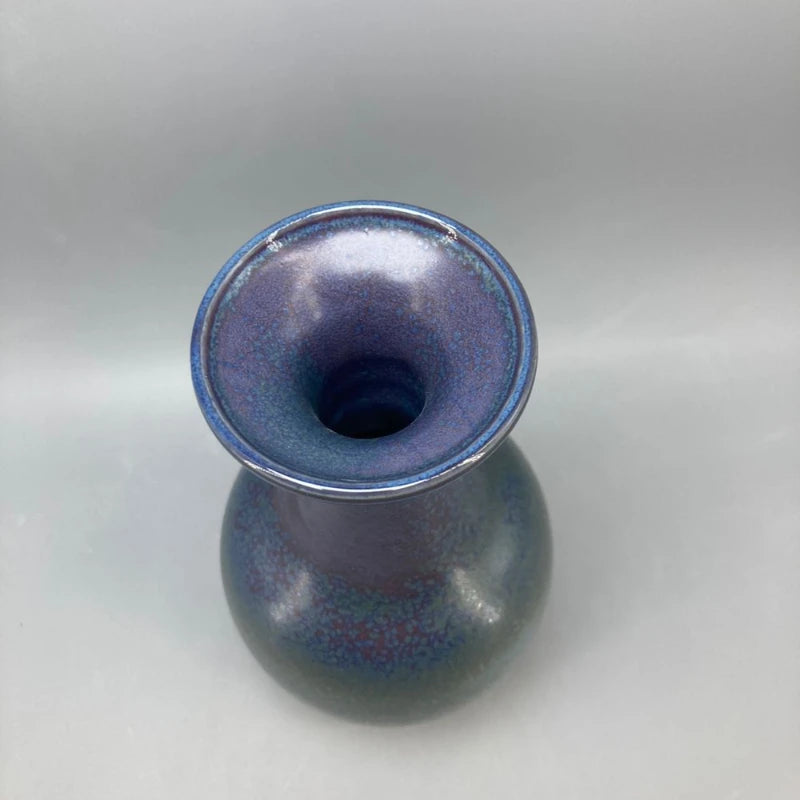 Un vase de couleur bleu-violet, avec un aspect brillant et nacré, présentant une forme ronde et élégante.