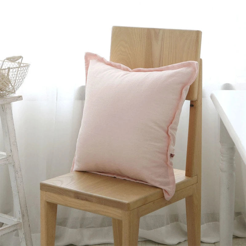 Un coussin rose posé sur une chaise en bois clair, créant une ambiance douce et chaleureuse dans la pièce.