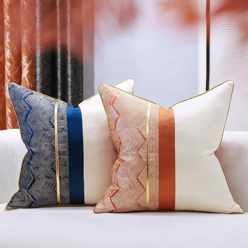 Des oreillers décoratifs avec des motifs géométriques colorés sur un canapé blanc, créant une ambiance chaleureuse et moderne dans une pièce ensoleillée.