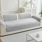 Canapé gris aux motifs géométriques élégants, placé dans un salon lumineux et épuré, complété par un meuble décoratif blanc.