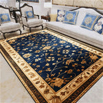 Tapis de sol de style oriental avec un motif floral délicat sur un fond bleu foncé, entouré d'une bordure beige et brune élégante, placé dans un salon cosy avec des meubles traditionnels.
