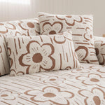 Coussin moelleux et douillet avec un motif floral stylisé en couleurs beige et marron, créant une ambiance chaleureuse et cocooning dans la pièce.