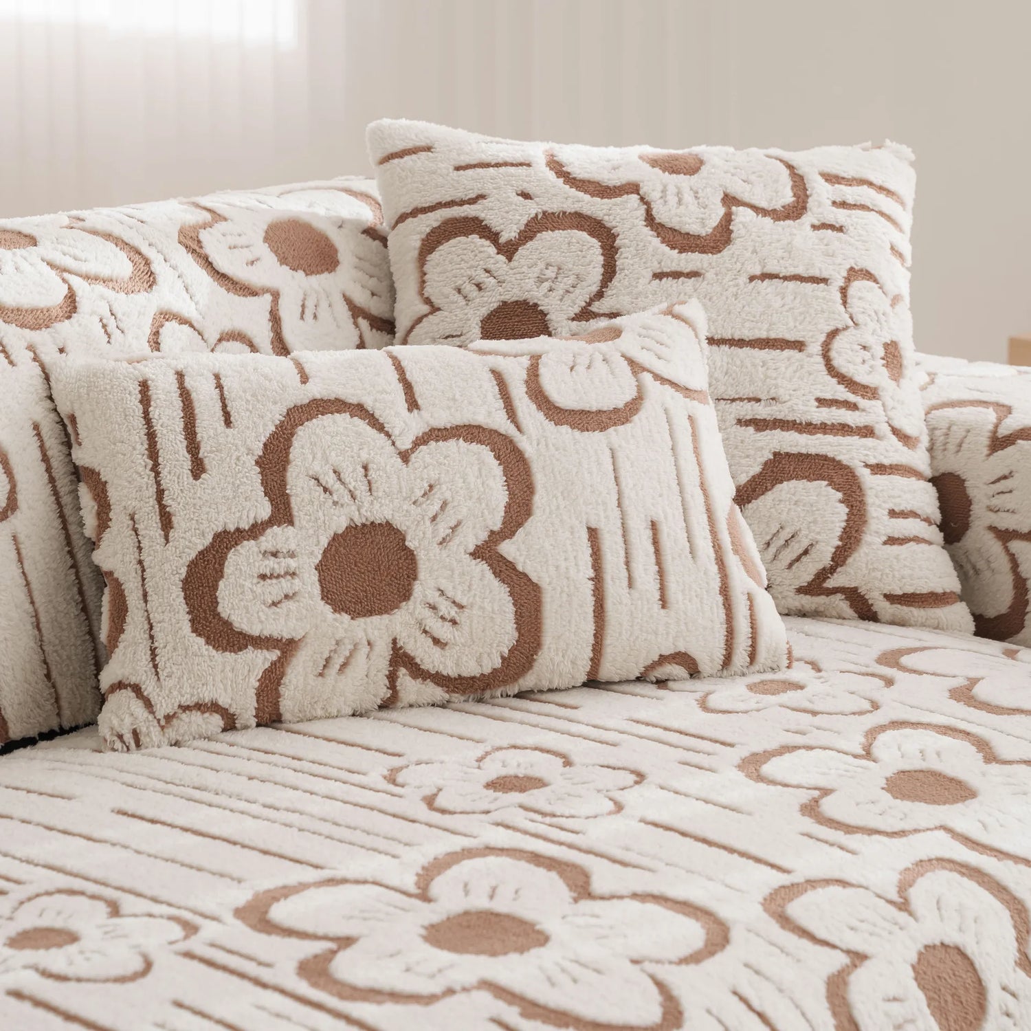 Coussin moelleux et douillet avec un motif floral stylisé en couleurs beige et marron, créant une ambiance chaleureuse et cocooning dans la pièce.