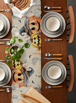 La table est joliment décorée avec des assiettes, des couverts et un chemin de table orné de motifs autommnaux.