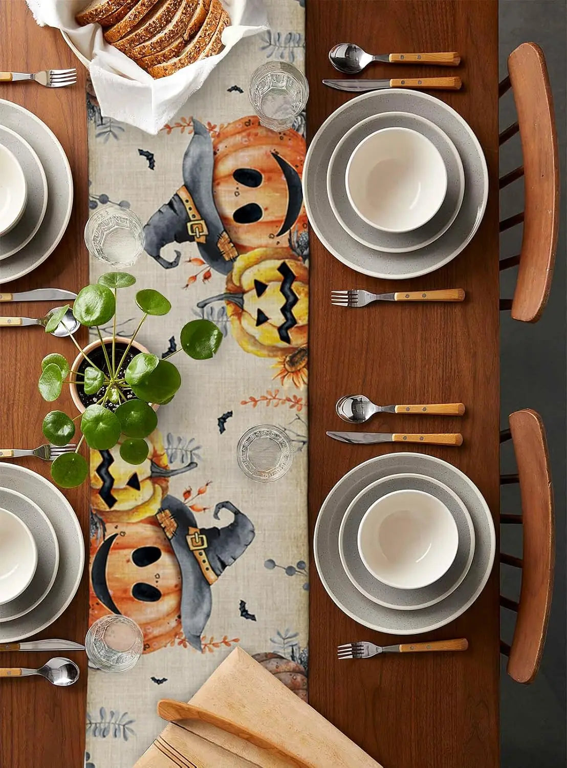 La table est joliment décorée avec des assiettes, des couverts et un chemin de table orné de motifs autommnaux.