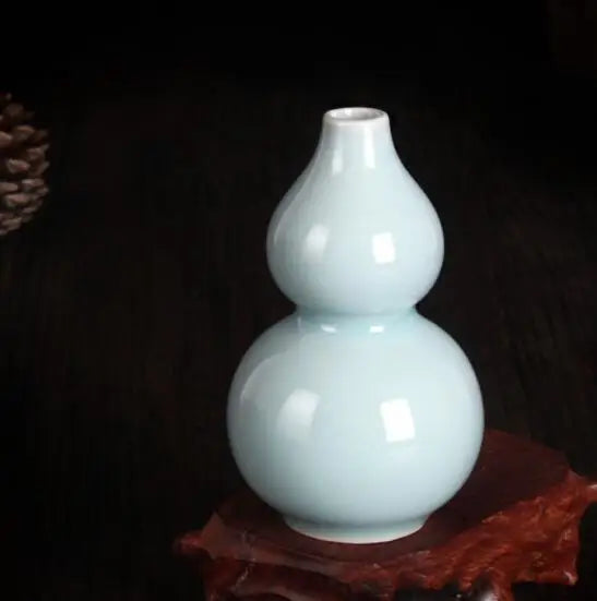 Vase de porcelaine de forme gourde de couleur bleu clair brillant sur un fond sombre.