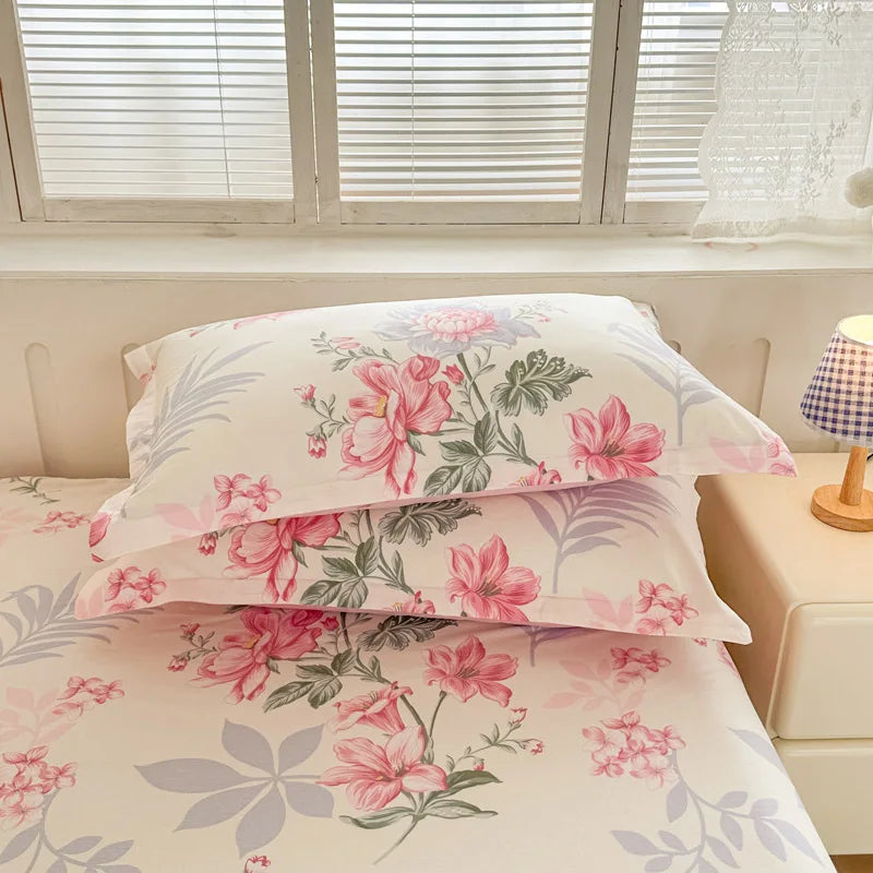 Lit douillet aux couleurs pastel avec de belles fleurs roses épanouies sur la parure de lit.