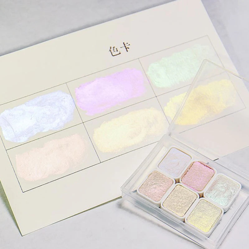 peintures aquarelle palette compacte bleu vert violet rose beige jaune blanc texture granuleuse opaques