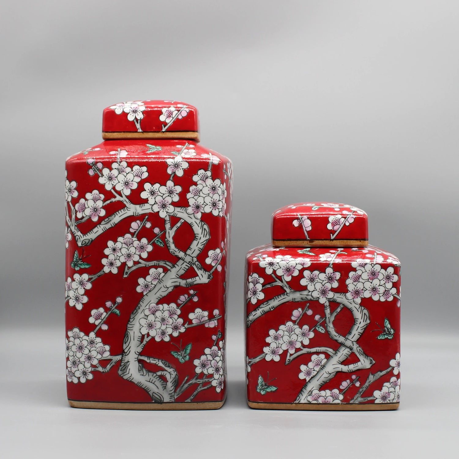 Deux boîtes en céramique décorées de motifs floraux typiques de la culture japonaise, dans des tons de rouge et blanc.