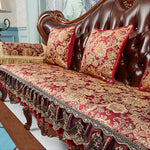 Un canapé de style vintage richement orné de motifs floraux dorés et de pompons sur un fond bordeaux, offrant une élégance et une décoration luxueuse à cette pièce.