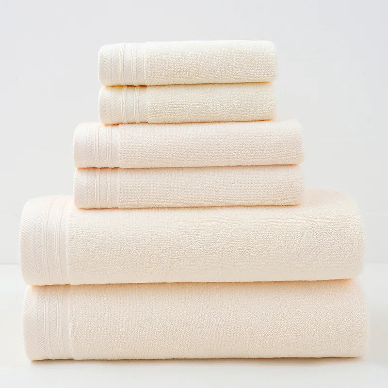 Pile de serviettes de bain moelleuses et blanches, empilées sur un fond uni.