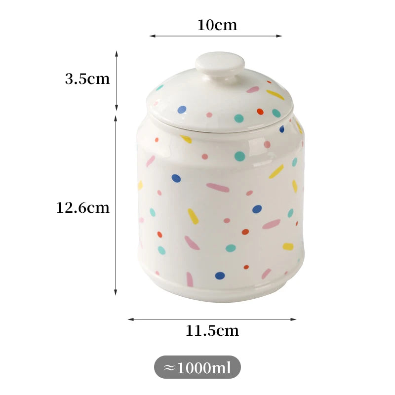 Pot de rangement en céramique blanc à motifs multicolores, mesurant 10 cm de largeur, 12,6 cm de hauteur et avec une capacité d'environ 1000 ml.