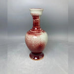 Vase en céramique de couleur blanche et rouge avec un motif d'éclaboussures sur un pied décoratif.