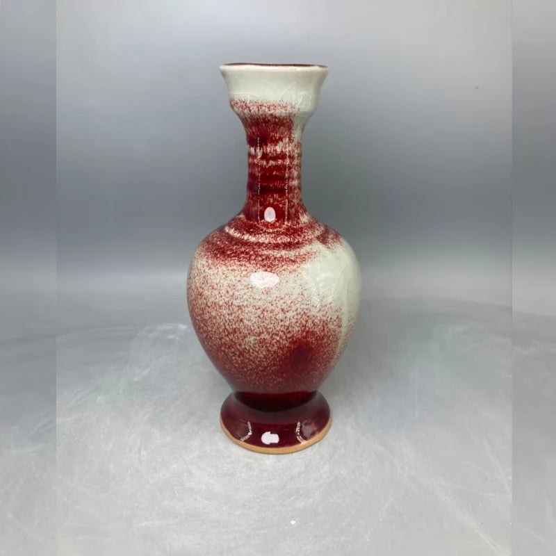 Vase en céramique de couleur blanche et rouge avec un motif d'éclaboussures sur un pied décoratif.