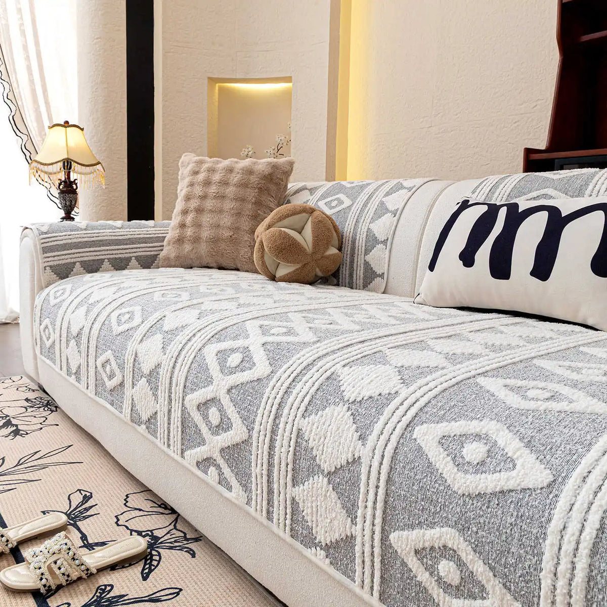 Un canapé confortable décoré de coussins et de motifs géométriques monochromes, offrant un espace douillet et chaleureux.