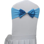 Une chaise blanche décorée d'un élégant nœud papillon bleu avec un ornement en strass au centre.