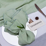 Un élégant sac cadeau enveloppé d'un papier vert menthe avec une inscription "CHARMING", posé sur une surface blanche.