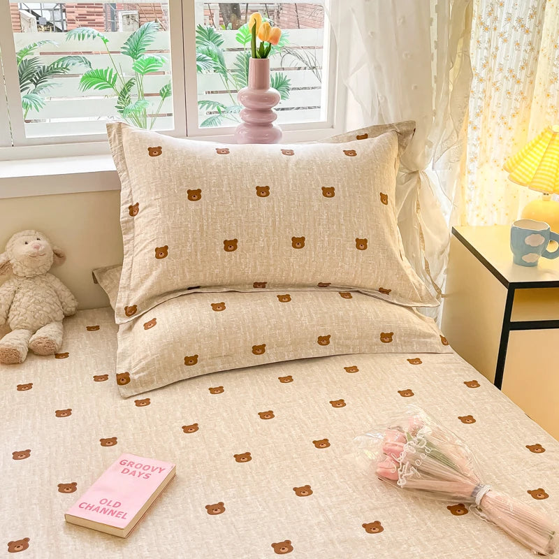 Un joli ensemble de literie composé d'un coussin et de draps imprimés de mignons petits ours, créant un environnement doux et chaleureux dans cette chambre.