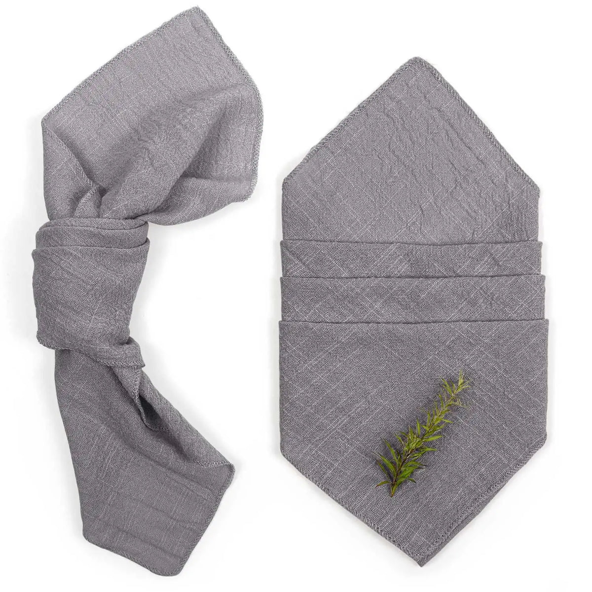 Des serviettes grises pliées, avec une brindille verte décorée, créant une atmosphère naturelle et apaisante.