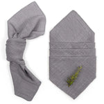 Des serviettes grises pliées, avec une brindille verte décorée, créant une atmosphère naturelle et apaisante.