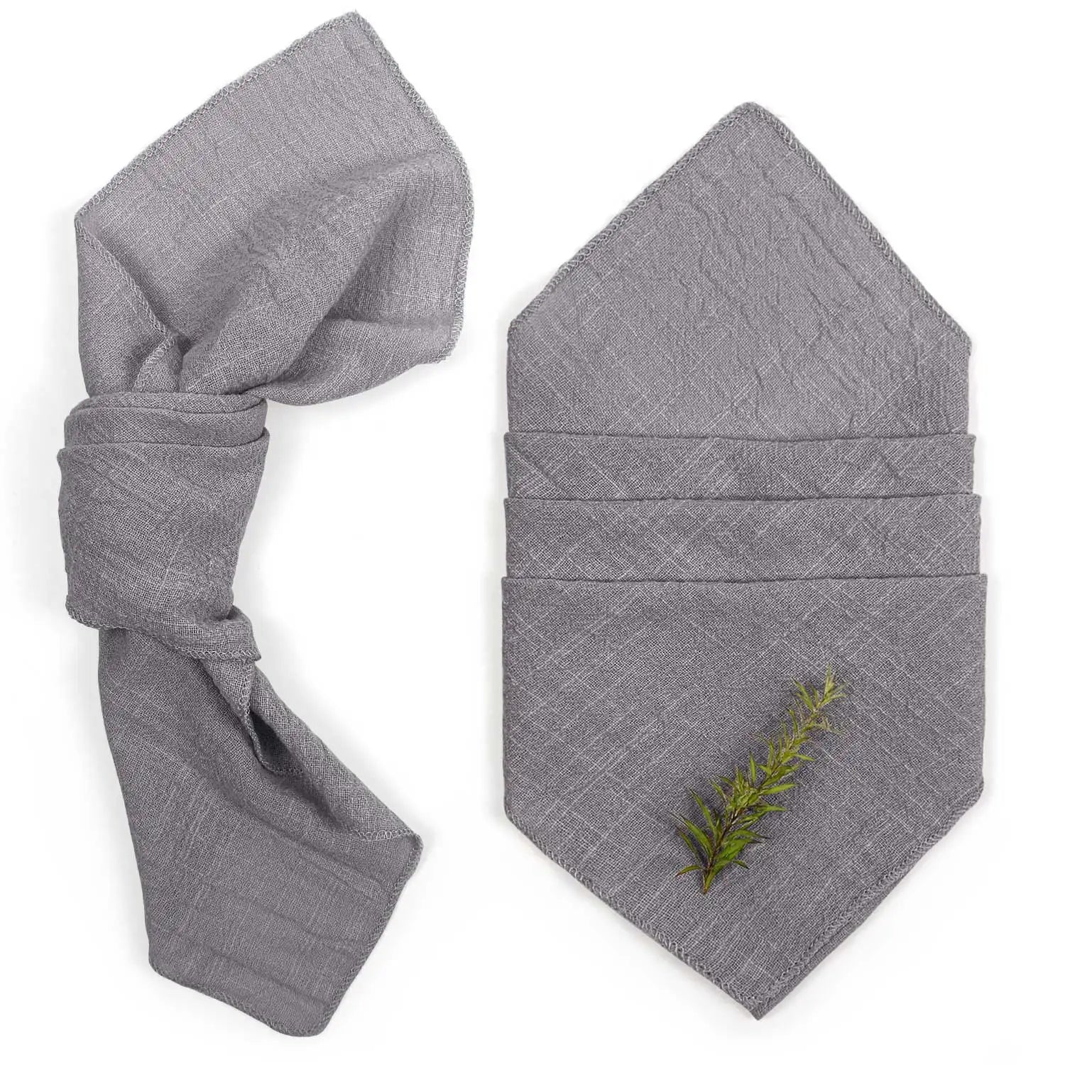 Des serviettes grises pliées, avec une brindille verte décorée, créant une atmosphère naturelle et apaisante.