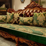 Luxueux canapé en bois sculpté avec des coussins ornés de motifs floraux et de motifs abstraits dorés sur fond vert.