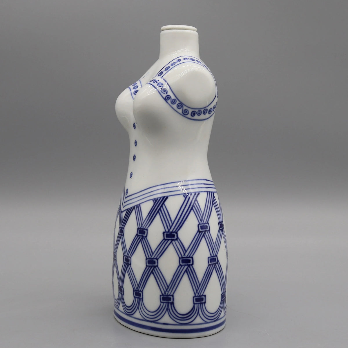 Photographie d'un vase de couleur blanche avec un motif bleu en forme de spirale et de rayures entrecroisées.