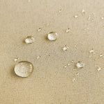 Gouttes d'eau sur un tissu beige, démontrant une surface résistante à l'humidité, idéal pour des applications extérieures et vêtements imperméables.