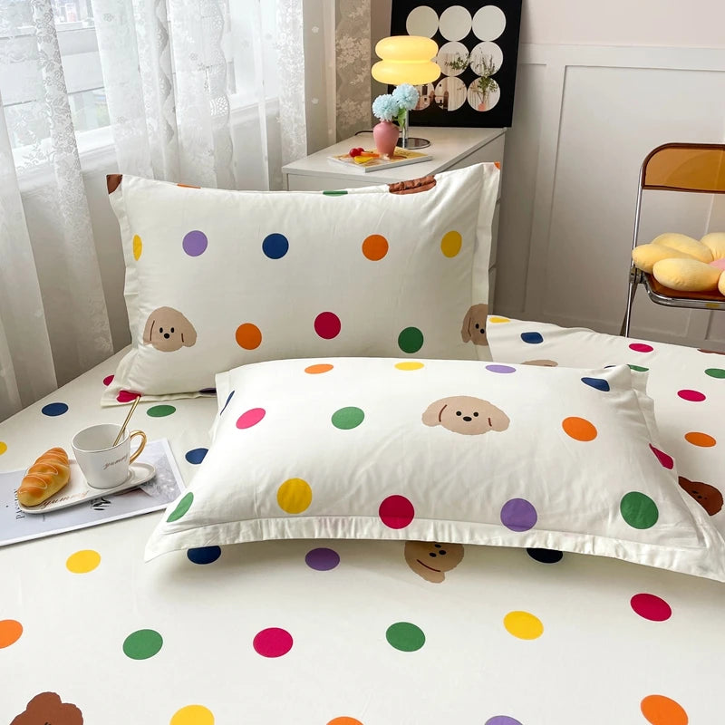 Parure de lit colorée avec des motifs de points colorés et de petits chiens mignons sur fond blanc, créant une ambiance joyeuse et ludique dans la chambre.