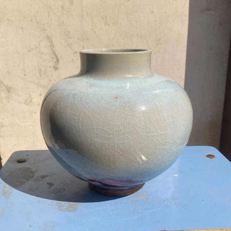 Vase en céramique vintage de couleur blanche avec des motifs craquelés, posé sur une surface en bois.
