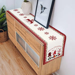 Mobilier en bois avec un chemin de table décoré de motifs de flocons de neige et de silhouettes de personnages de Noël.