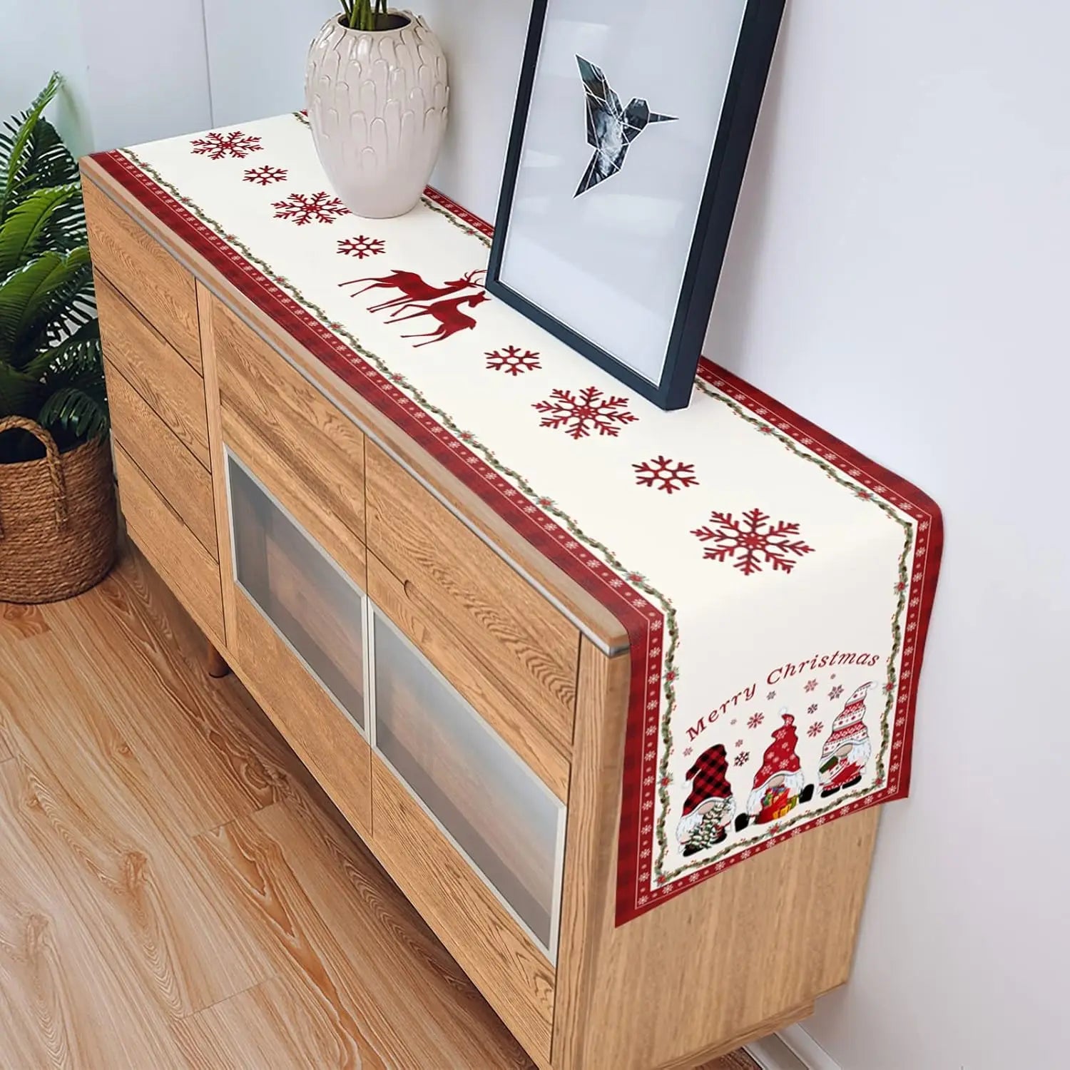 Mobilier en bois avec un chemin de table décoré de motifs de flocons de neige et de silhouettes de personnages de Noël.