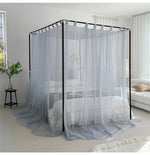 Cette image montre un lit à baldaquin avec des rideaux gris qui l'entourent, créant un effet cocooning et relaxant dans la pièce.