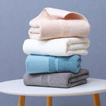 Une pile de serviettes douces et moelleuses de différentes couleurs, disposées sur une table blanche.
