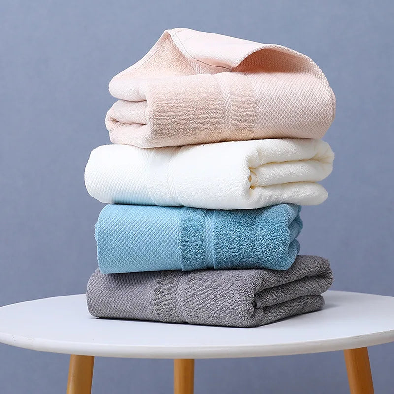 Une pile de serviettes douces et moelleuses de différentes couleurs, disposées sur une table blanche.