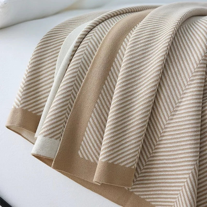 Cette couverture en tricot beige pâle présente un motif de rayures horizontales subtiles, offrant une texture douce et accueillante.