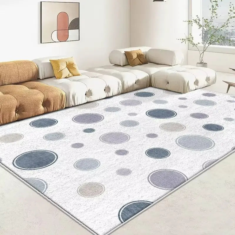 Tapis décoratif moucheté de diverses teintes de gris et de blanc, posé dans un salon moderne avec des canapés et un tableau abstrait au mur.