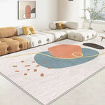 Cette image présente un aménagement intérieur moderne et coloré, avec un tapis orné de formes géométriques et des canapés confortables dans des tons crème et dorés.