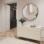 Entrée élégante avec miroir rond encadré, commode blanche et plante verte, dans un décor aux couleurs douces et naturelles.