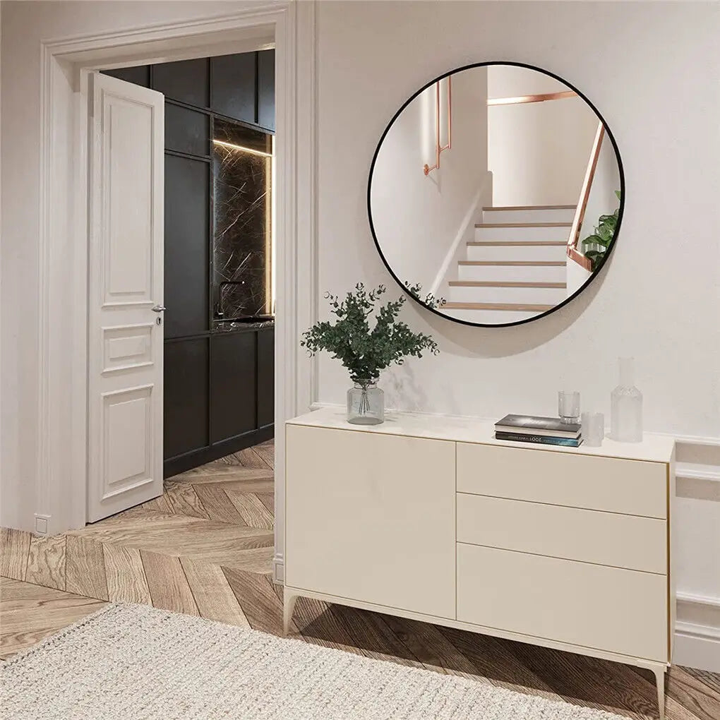 Entrée élégante avec miroir rond encadré, commode blanche et plante verte, dans un décor aux couleurs douces et naturelles.