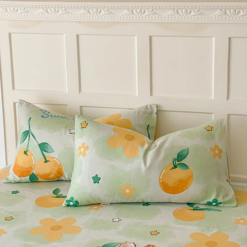 Taie d'oreiller décorative avec imprimé de fruits et de fleurs sur fond vert clair, créant une ambiance fraîche et printanière dans la chambre.