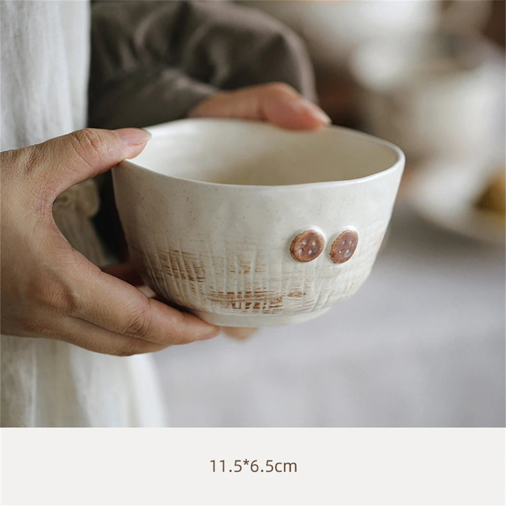 Bol en céramique blanc avec des motifs texturés et des anses en forme de boutons.