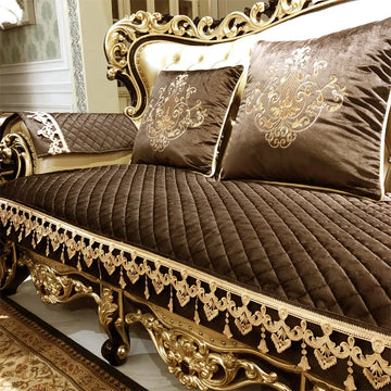 Un canapé de style baroque orné de détails dorés et de coussins en tissu brun foncé imprimé de motifs élégants.