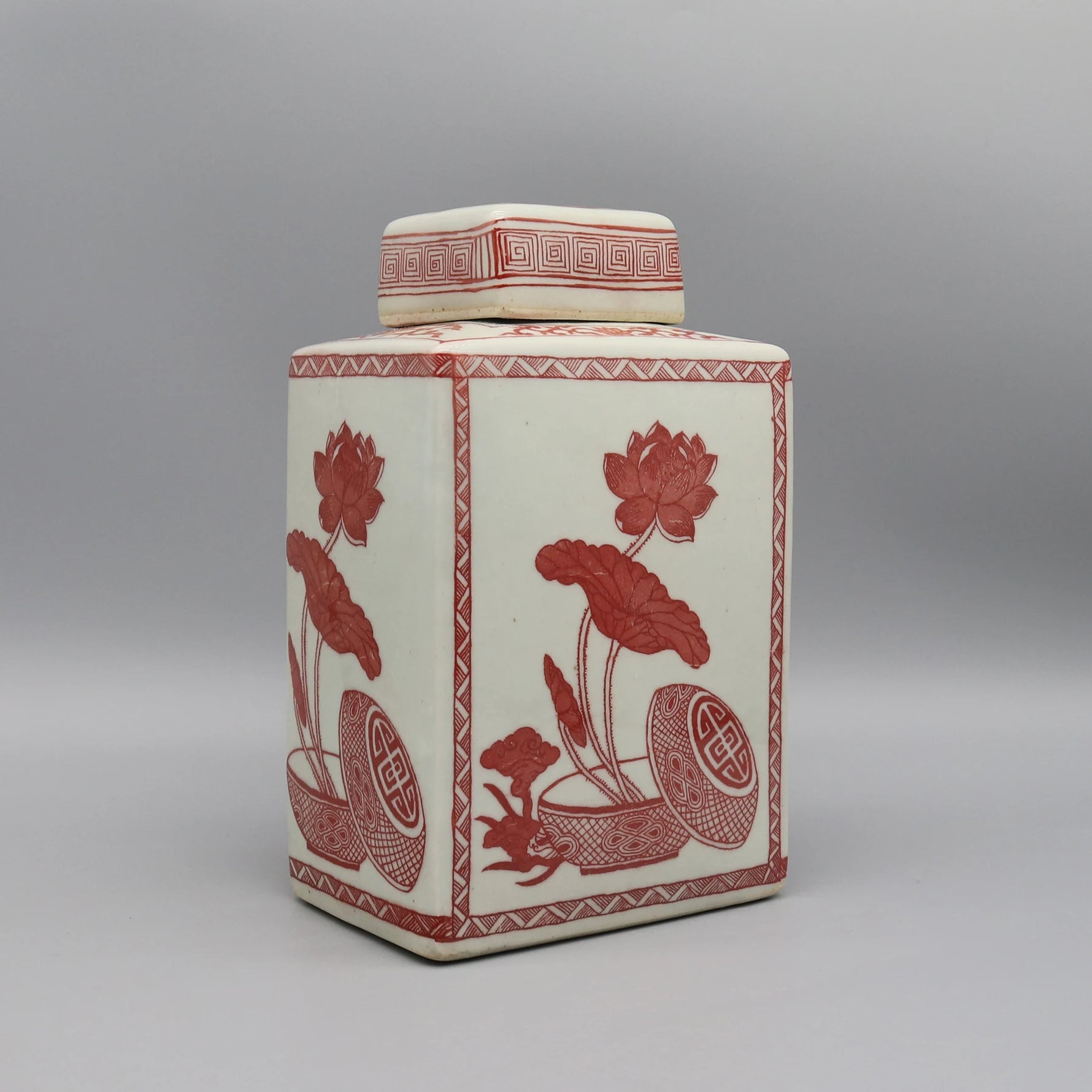 Pot décoratif en céramique blanc avec motifs floraux rouges et motifs géométriques.