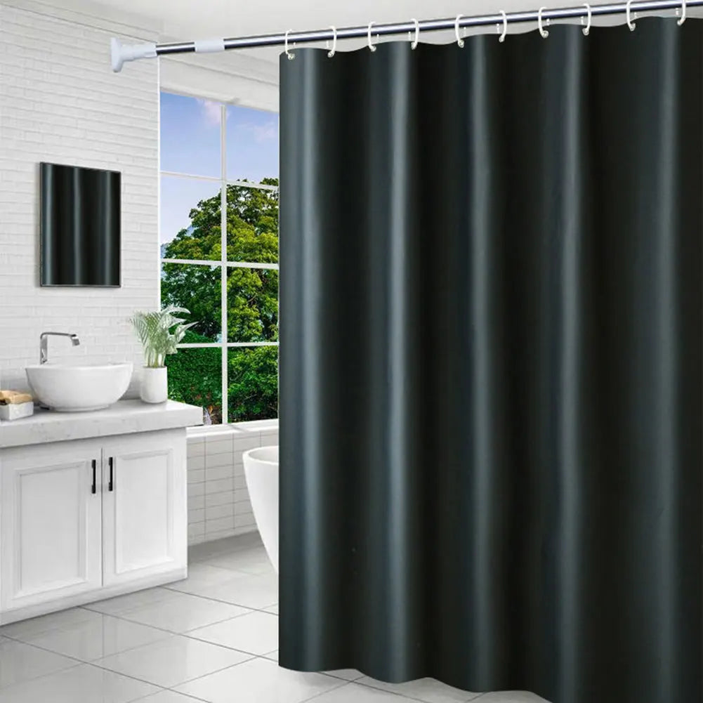 Salle de bain lumineuse avec un rideau de douche de couleur noire, contrastant avec le mobilier blanc et une grande fenêtre donnant sur un espace vert. 