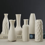 Arrangement élégante de vases en céramique blanche aux formes variées sur fond sombre, créant une atmosphère épurée et minimaliste.