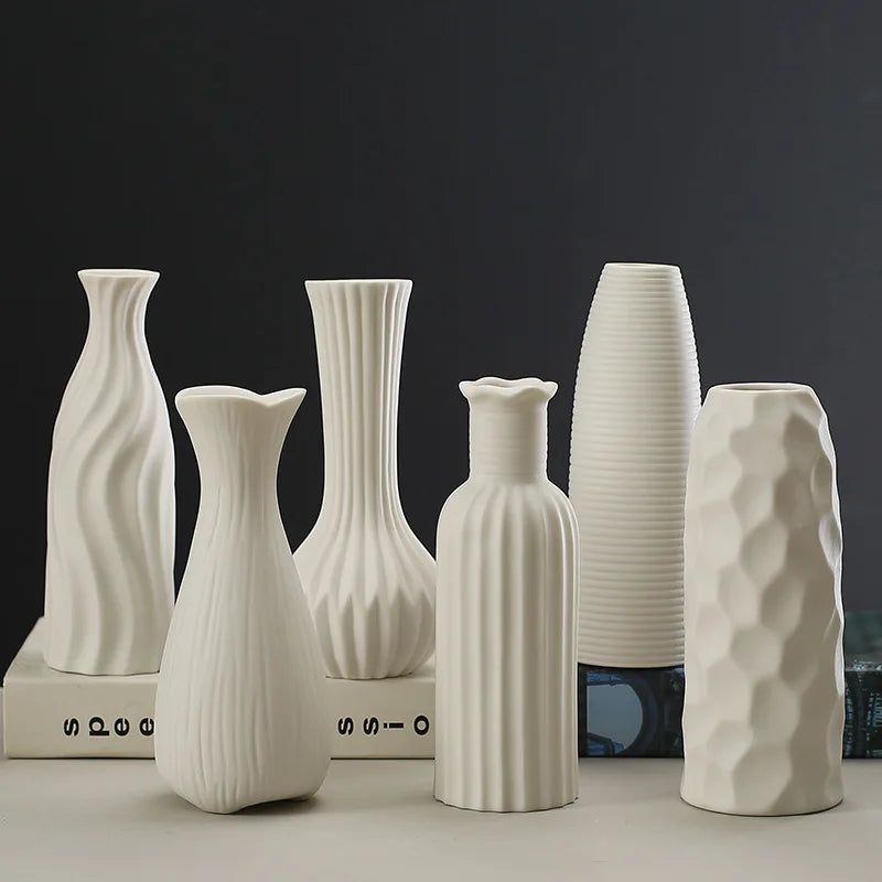 Arrangement élégante de vases en céramique blanche aux formes variées sur fond sombre, créant une atmosphère épurée et minimaliste.