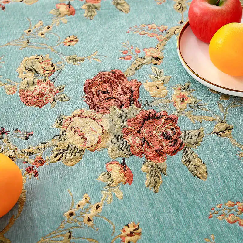 Un tapis bleu clair avec des motifs floraux artistiques et colorés, comprenant des roses rouges et d'autres fleurs, créant une atmosphère chaleureuse et élégante.