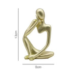 statue décorative moderne figure humaine assise couleur or noir beige.texture granuleuse surface lisseintérieur moderne