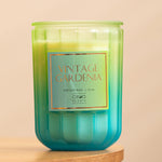 Bougie parfumée verte intitulée "Vintage Gardenia" de la marque Circa Scents, avec un contenant en verre et une étiquette orange indiquant la composition en cire de soja à 95%.